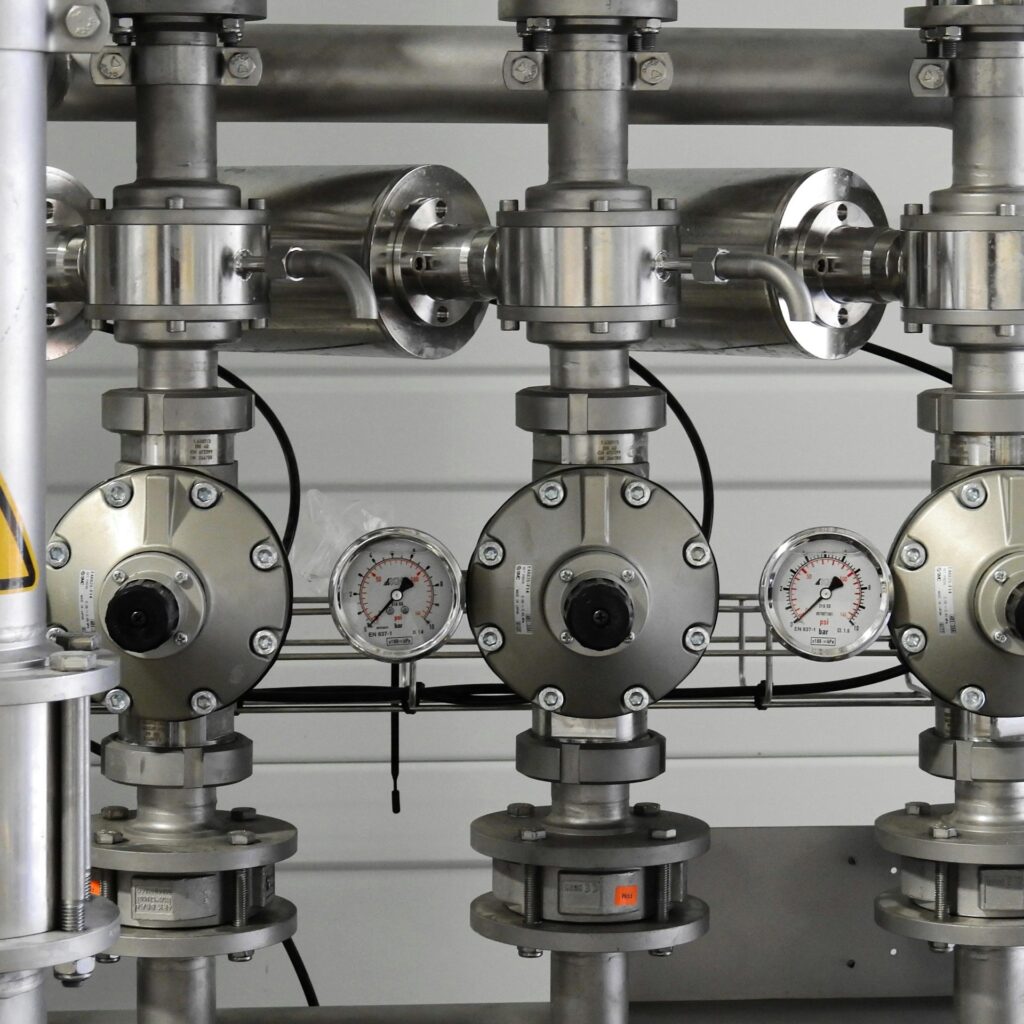 Close-up of stainless steel pipes with pressure gauges in an industrial setting.